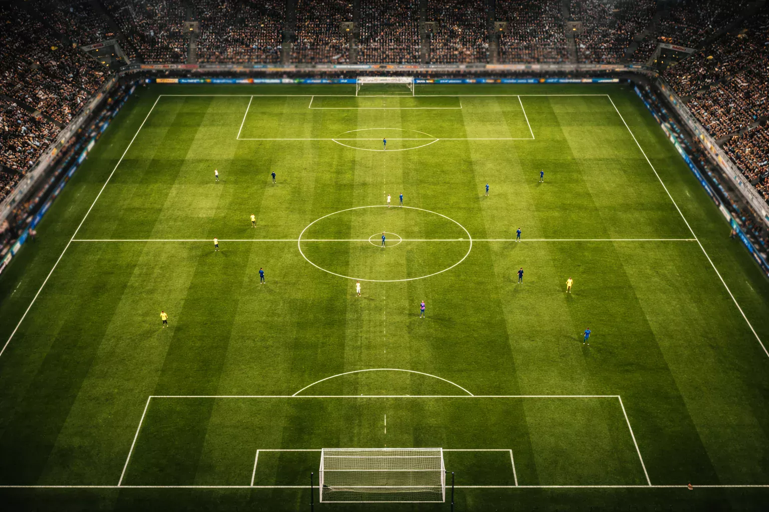 Giocatori di calcio in azione su campo verde durante una partita vista dall'alto